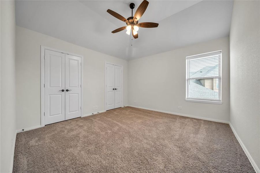 Unfurnished bedroom with multiple closets, carpet, a ceiling fan, and vaulted ceiling Unfurnished bedroom with multiple closets, carpet, a ceiling fan, and vaulted ceiling