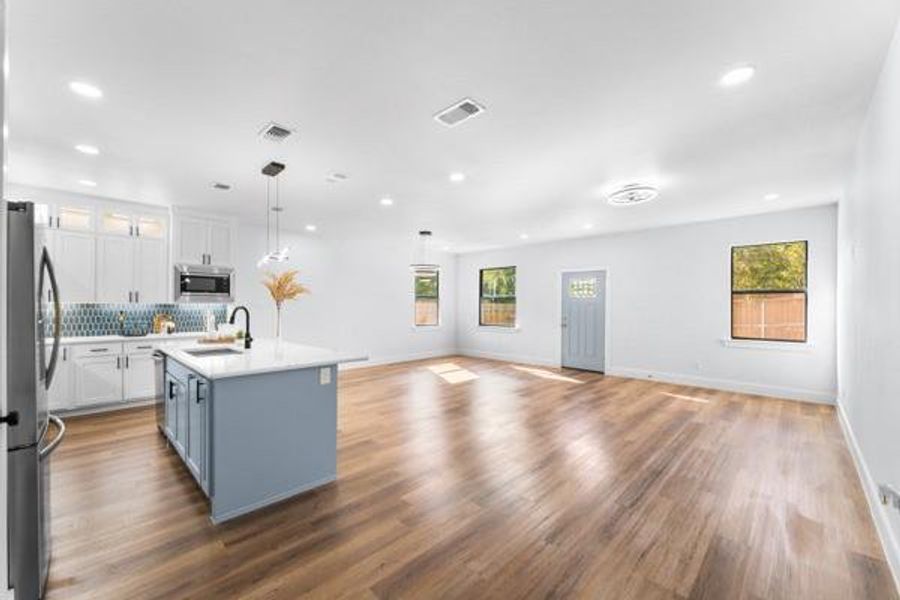 Kitchen with white cabinets, stainless steel appliances, a kitchen island with sink, tasteful backsplash, and dark wood-type flooring Kitchen with white cabinets, stainless steel appliances, a kitchen island with sink, tasteful backsplash, and dark wood-type flooring