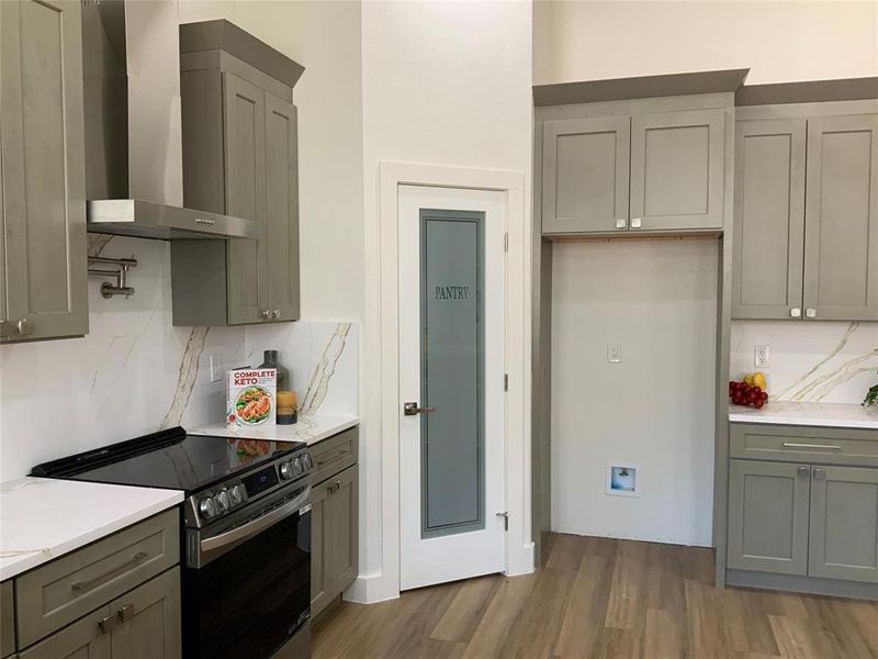Kitchen featuring stainless steel range with electric stovetop, gray cabinets, dark wood-style flooring, backsplash, and light stone counters Kitchen featuring stainless steel range with electric stovetop, gray cabinets, dark wood-style flooring, backsplash, and light stone counters