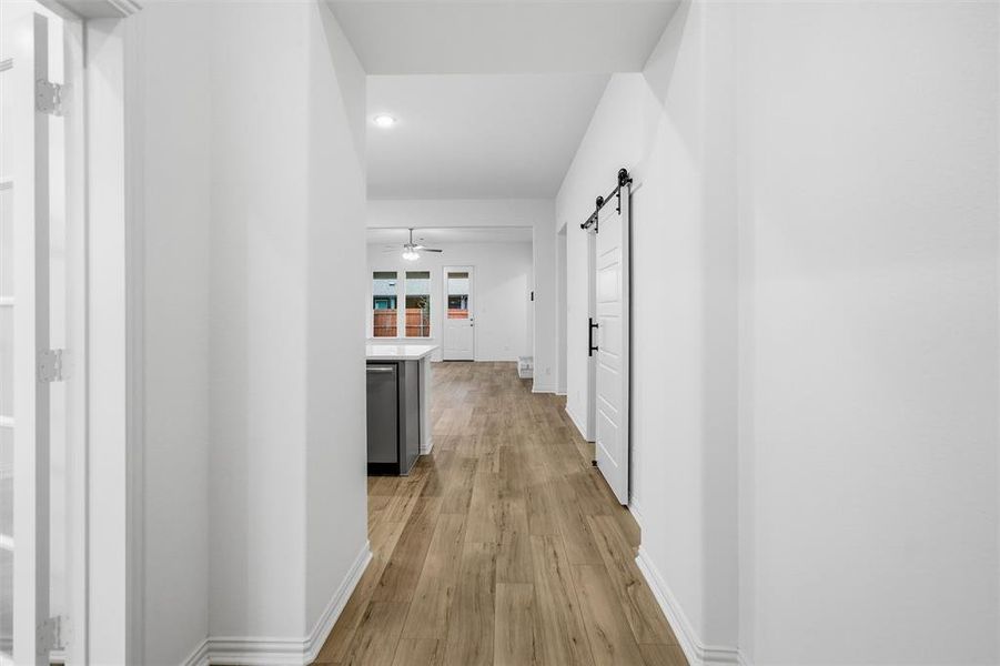 Corridor with a barn door, light wood finished floors, and recessed lighting