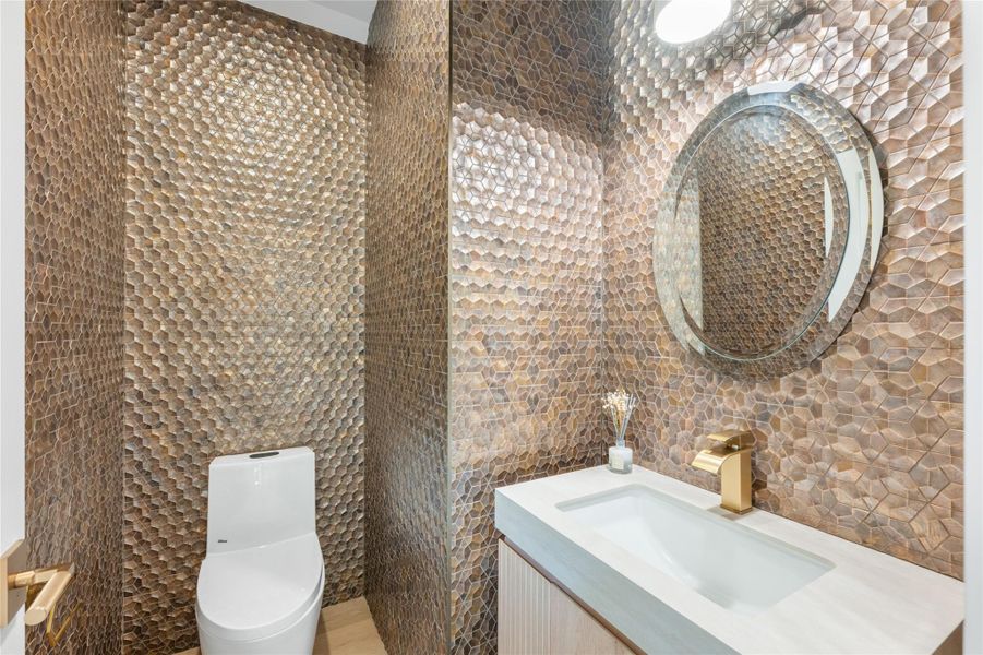 Refined powder room featuring unique textured tile walls and contemporary fixtures. Refined powder room featuring unique textured tile walls and contemporary fixtures.
