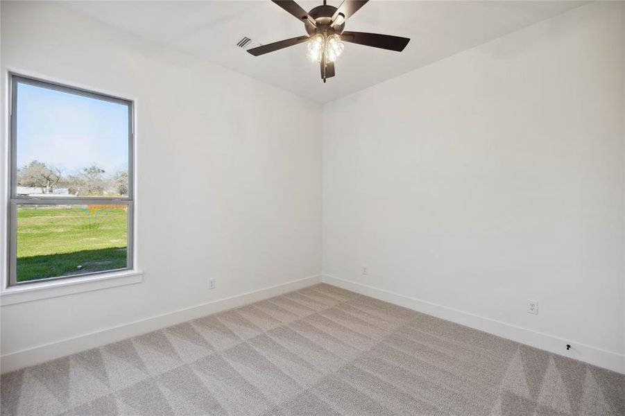 Empty room featuring light carpet, plenty of natural light, and ceiling fan