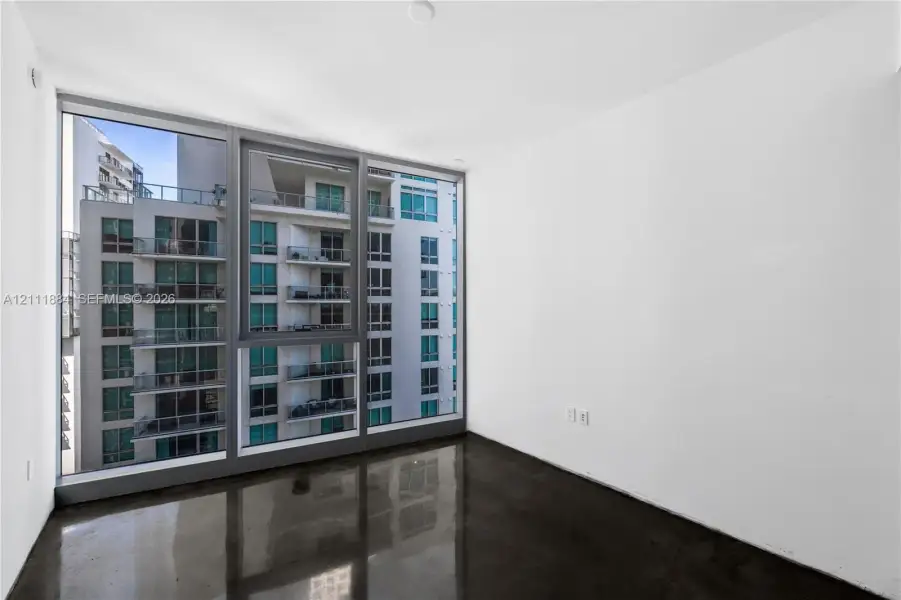 Floor-to-ceiling windows with dark framing, polished concrete flooring, and neutral white walls Floor-to-ceiling windows with dark framing, polished concrete flooring, and neutral white walls