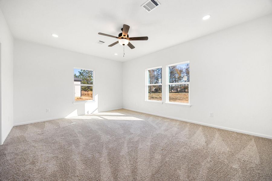 Spacious primary bedroom with abundant natural light, soft carpeting, and a modern ceiling fan for comfort and style. Spacious primary bedroom with abundant natural light, soft carpeting, and a modern ceiling fan for comfort and style.