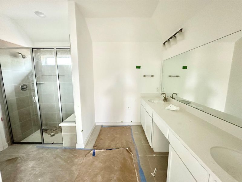 Full bath featuring double vanity and a stall shower