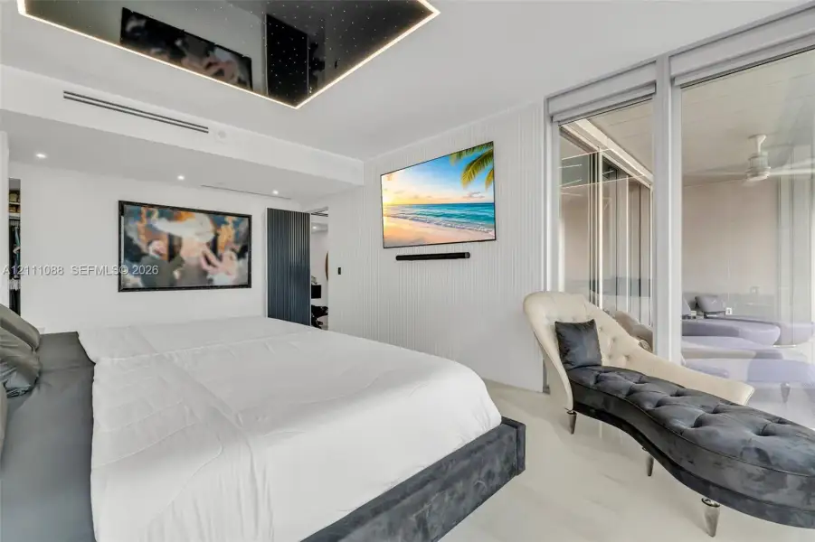 Custom coffered ceiling with integrated recessed lighting, vertical wall paneling, floor-to-ceiling glass sliding doors, and polished stone flooring Custom coffered ceiling with integrated recessed lighting, vertical wall paneling, floor-to-ceiling glass sliding doors, and polished stone flooring