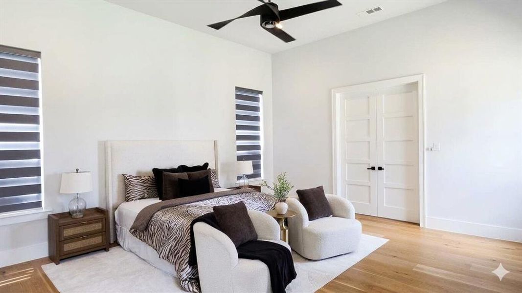 Spacious room featuring light wood-finish flooring, white walls, and a high ceiling with a contemporary ceiling fan