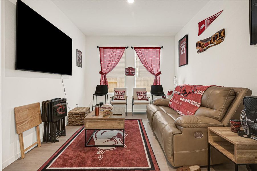 Cozy entertainment room featuring a large TV, comfortable recliner sofa, and team-themed decor, perfect for sports enthusiasts. Cozy entertainment room featuring a large TV, comfortable recliner sofa, and team-themed decor, perfect for sports enthusiasts.