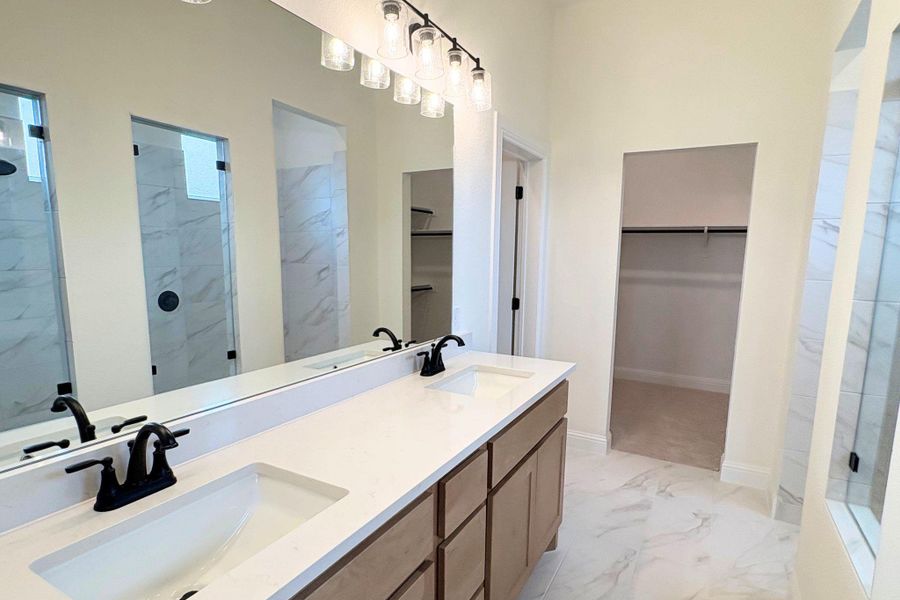 Gleaming stone counters and marble-style tile floors define this refined primary bath layout. Gleaming stone counters and marble-style tile floors define this refined primary bath layout.