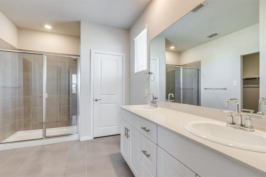 Full bathroom featuring double vanity, light tile patterned floors, a shower stall, recessed lighting, and a walk in closet