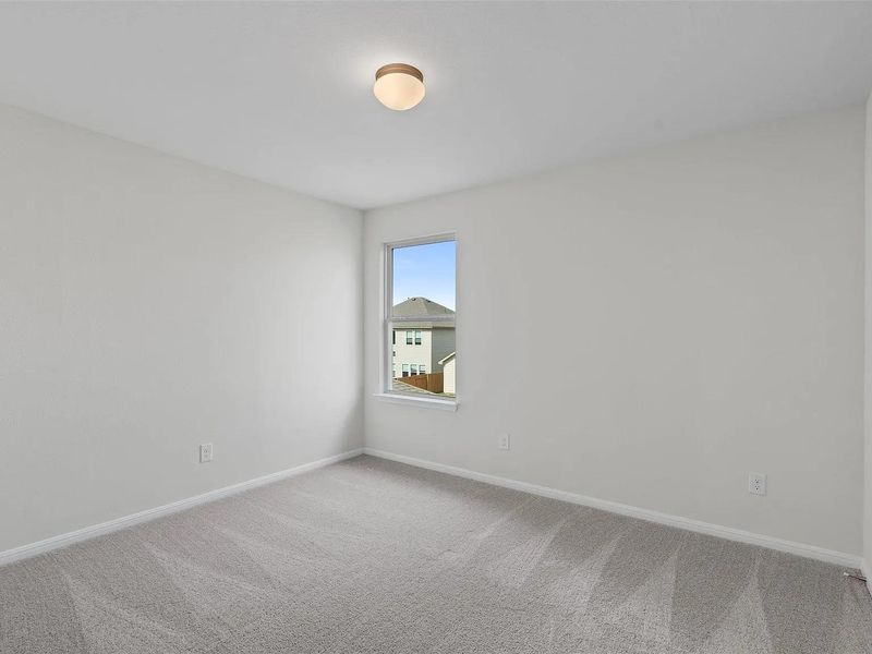 An airy bedroom provides a tranquil space with plush carpet and ample natural illumination.