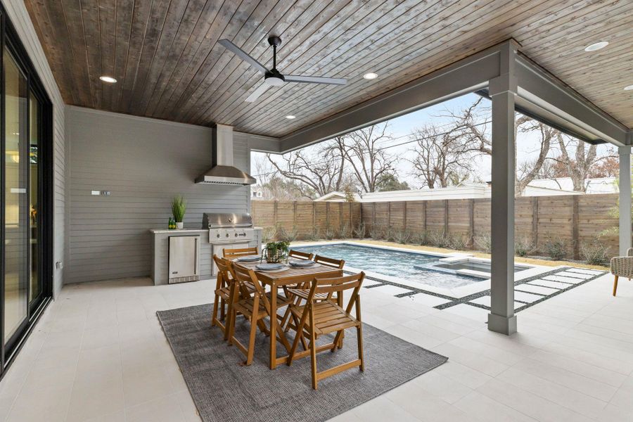 Fenced backyard with a ceiling fan, a patio, outdoor dining area, and a pool with connected hot tub