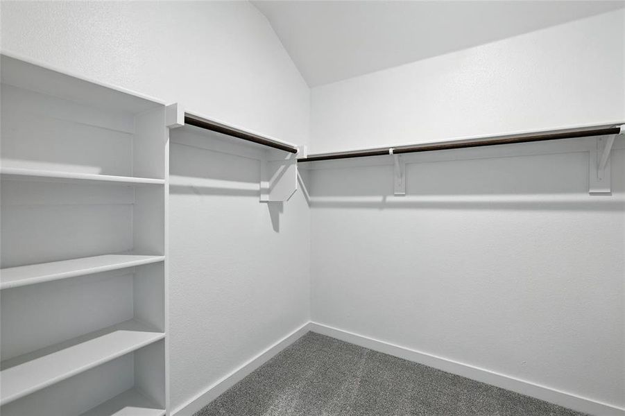 Walk in closet featuring dark carpet and lofted ceiling Walk in closet featuring dark carpet and lofted ceiling