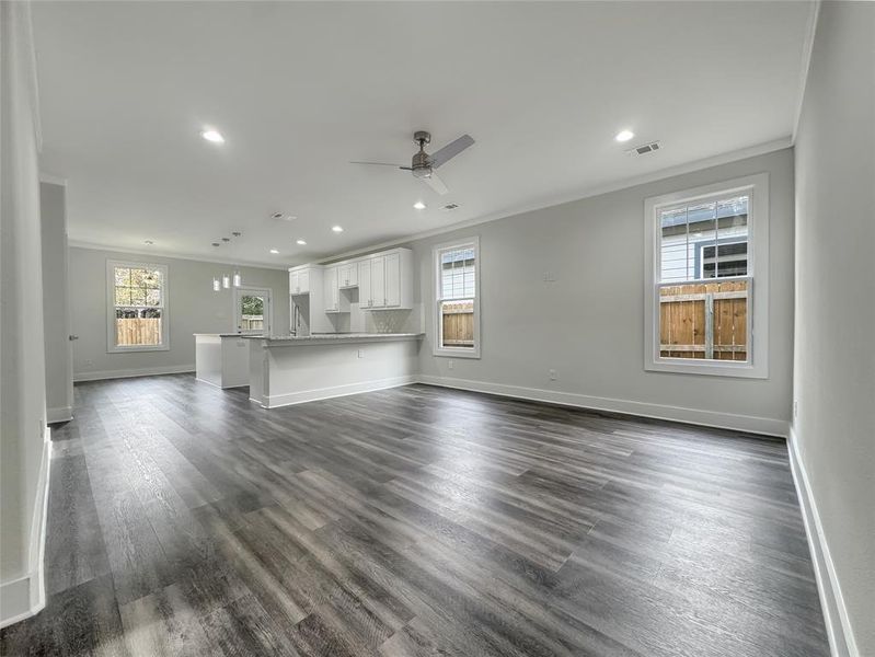 Unfurnished living room featuring ornamental molding, recessed lighting, a ceiling fan, dark wood-type flooring, and a chandelier