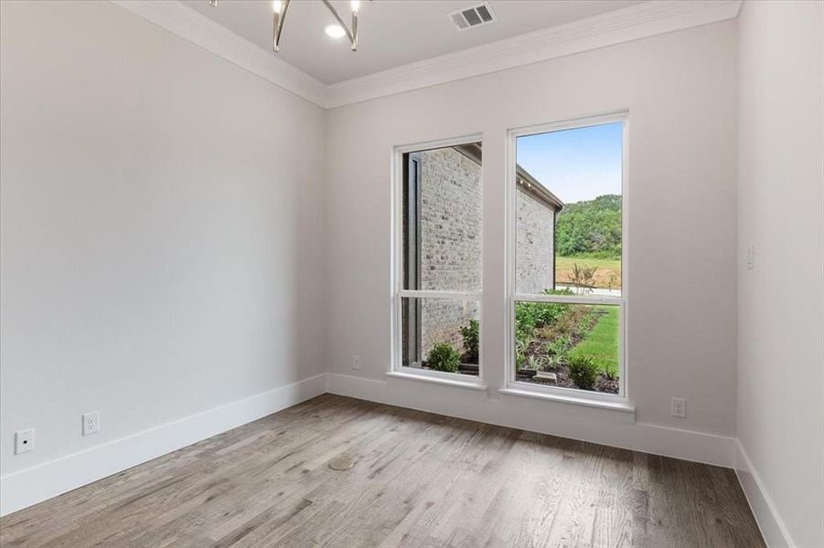 Unfurnished room featuring a notable chandelier, ornamental molding, and light hardwood / wood-style flooring