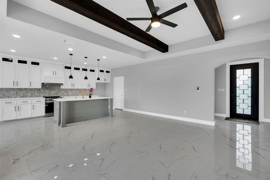 Kitchen with tasteful backsplash, beam ceiling, white cabinets, decorative light fixtures, and stainless steel range oven