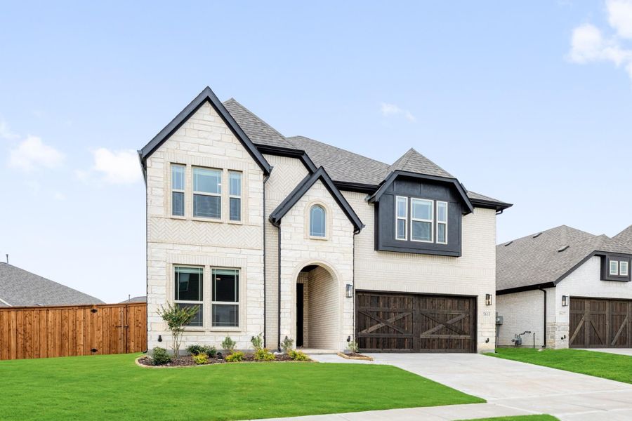Two-story home with white brick exterior, dark trim, arched entry, and two-car garage with wood doors Two-story home with white brick exterior, dark trim, arched entry, and two-car garage with wood doors