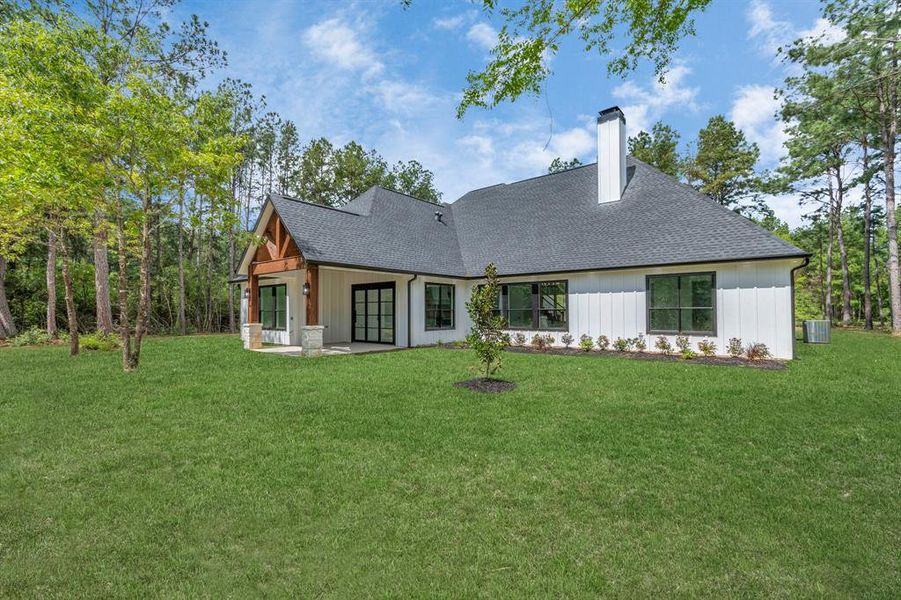 Explore the tranquil backyard oasis framed by lush woods, complementing the home's elegant rear facade.