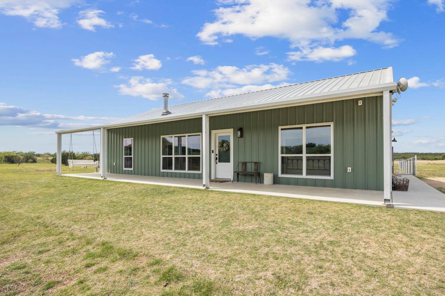 Back of property featuring board and batten siding, a yard, and a metal roof