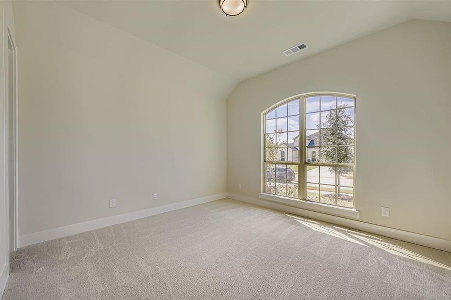 Empty room featuring vaulted ceiling and light colored carpet