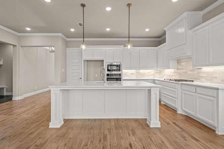 Kitchen featuring backsplash, ornamental molding, recessed lighting, decorative light fixtures, and white cabinetry Kitchen featuring backsplash, ornamental molding, recessed lighting, decorative light fixtures, and white cabinetry