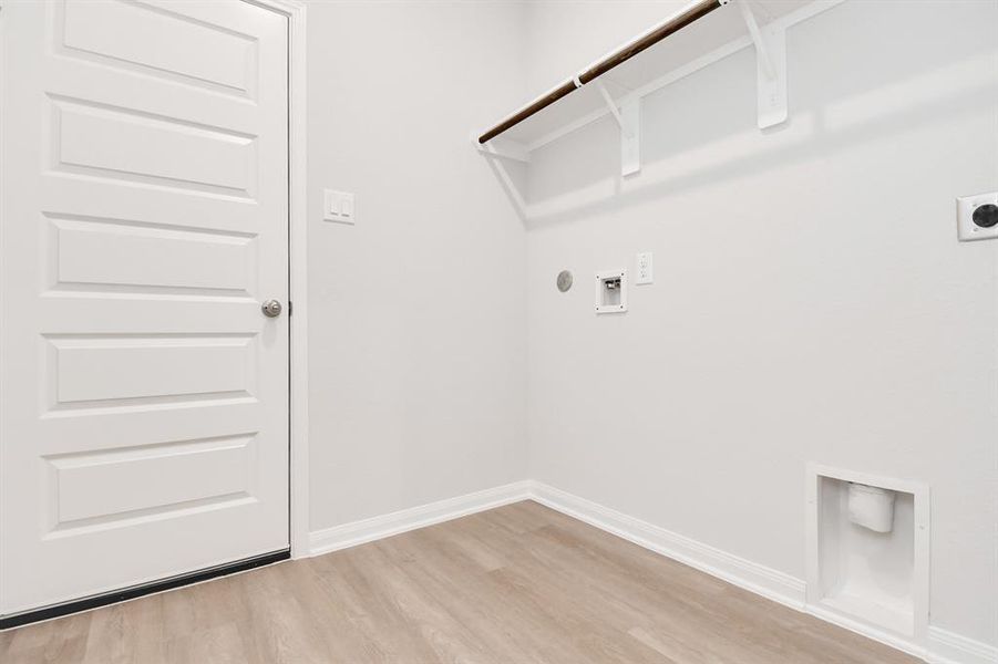 A spacious utility room with ample shelving for organization. It features connections forboth gas and electric dryers, making it versatile and functional for all laundry needs.