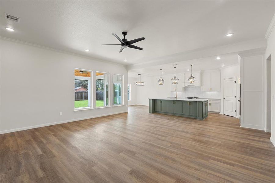 Unfurnished living room featuring ornamental molding, a ceiling fan, dark wood-style flooring, and recessed lighting Unfurnished living room featuring ornamental molding, a ceiling fan, dark wood-style flooring, and recessed lighting
