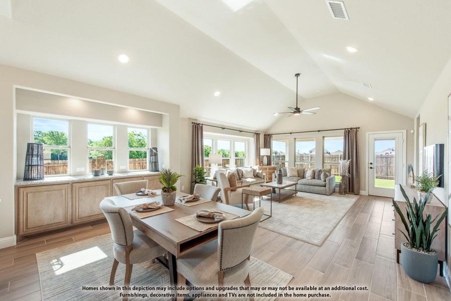 Open-concept dining and living area with vaulted ceiling, hardwood floors, and large windows