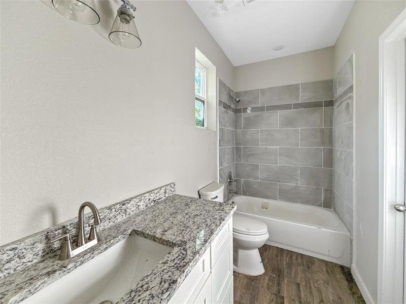 Bathroom with vanity, dark wood-style flooring, and shower / washtub combination