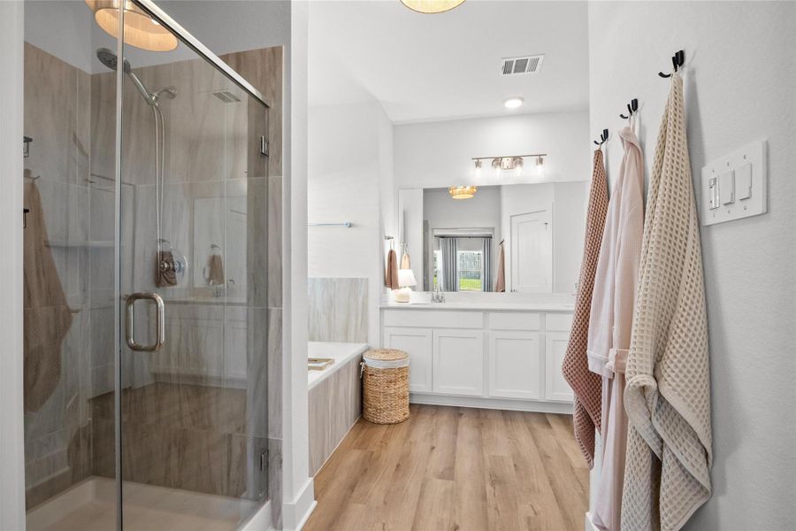 Spa-like primary bathroom featuring a spacious glass-enclosed shower, soaking tub, oversized vanity, and bright modern finishes—creating the perfect space to refresh and unwind