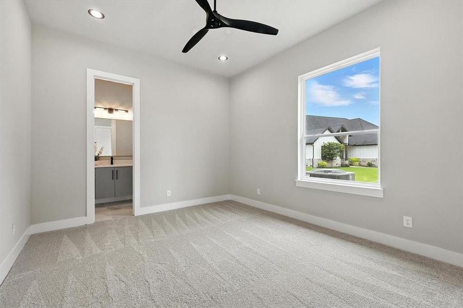 Unfurnished bedroom with light colored carpet, recessed lighting, ensuite bathroom, and ceiling fan Unfurnished bedroom with light colored carpet, recessed lighting, ensuite bathroom, and ceiling fan