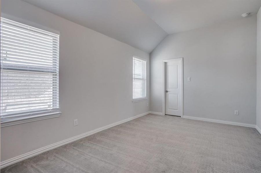 Carpeted empty room featuring lofted ceiling