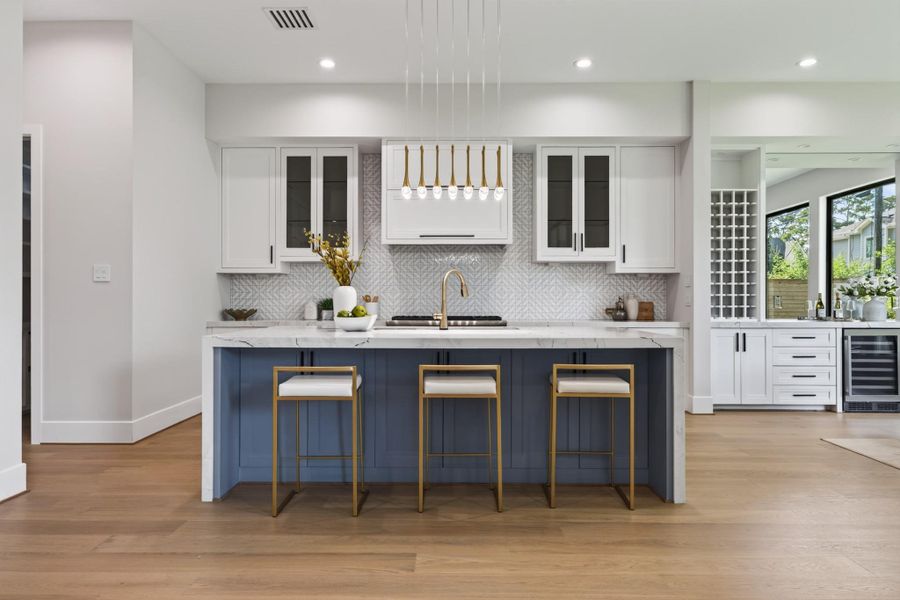 Chef's kitchen featuring navy custom cabinetry, waterfall quartz island, and premium stainless appliances.