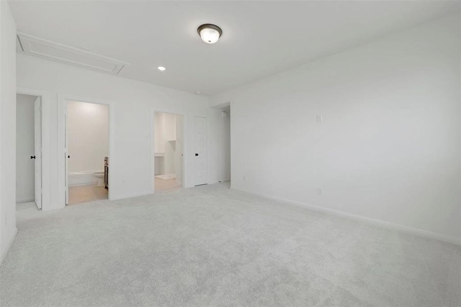 Spacious carpeted room featuring a ceiling-mounted light fixture, recessed lighting, and multiple doorways