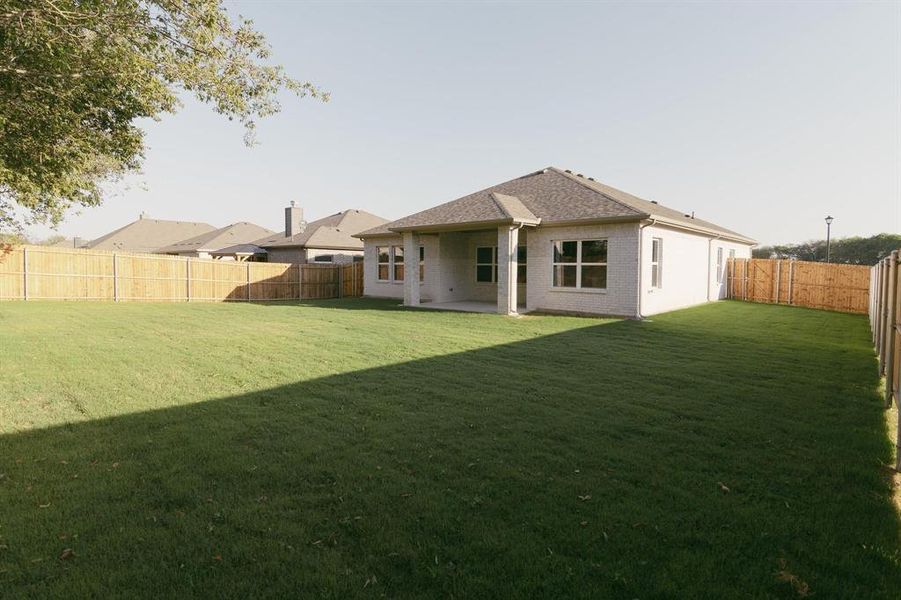 Back of property featuring brick siding, a patio area, a fenced backyard, and a shingled roof