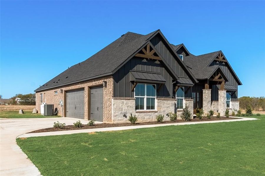 View of front facade featuring central AC unit, a garage, and a front yard