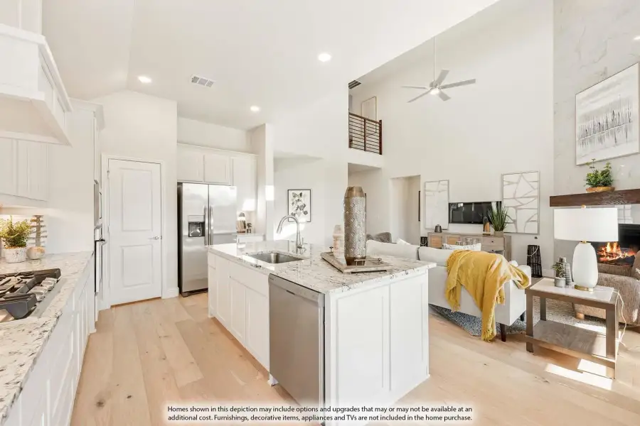Open-concept kitchen with white island, granite countertops, and living room with fireplace and high ceilings