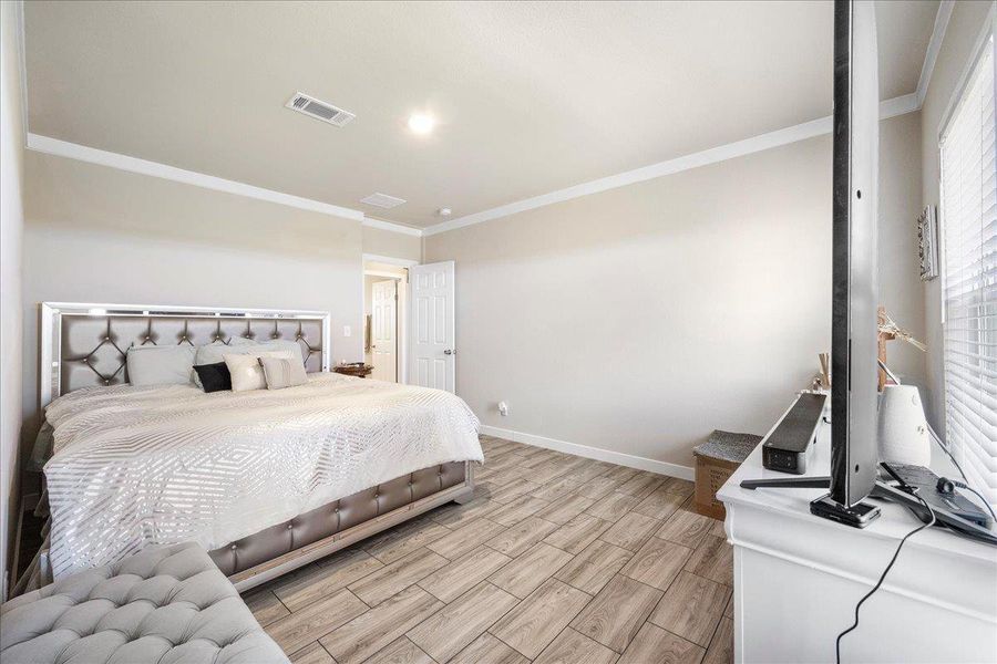 Bedroom featuring wood finish floors and crown molding Bedroom featuring wood finish floors and crown molding