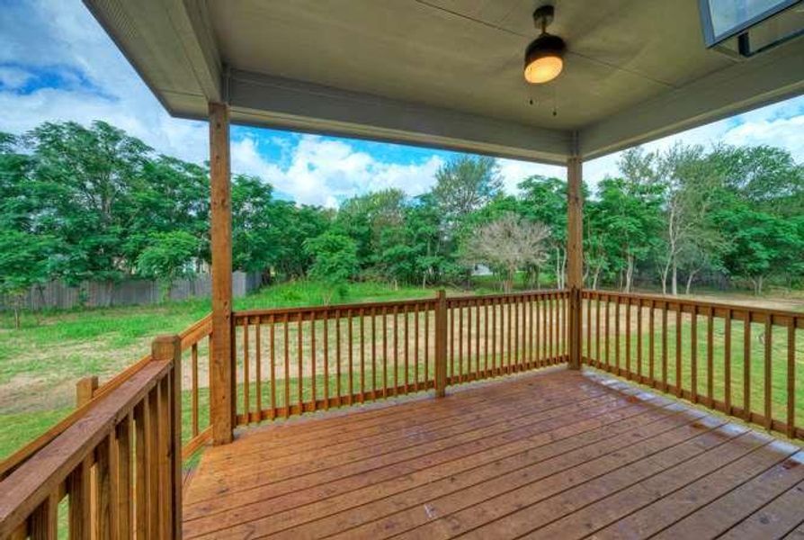 A spacious covered deck offers serene views of the verdant yard and mature trees.