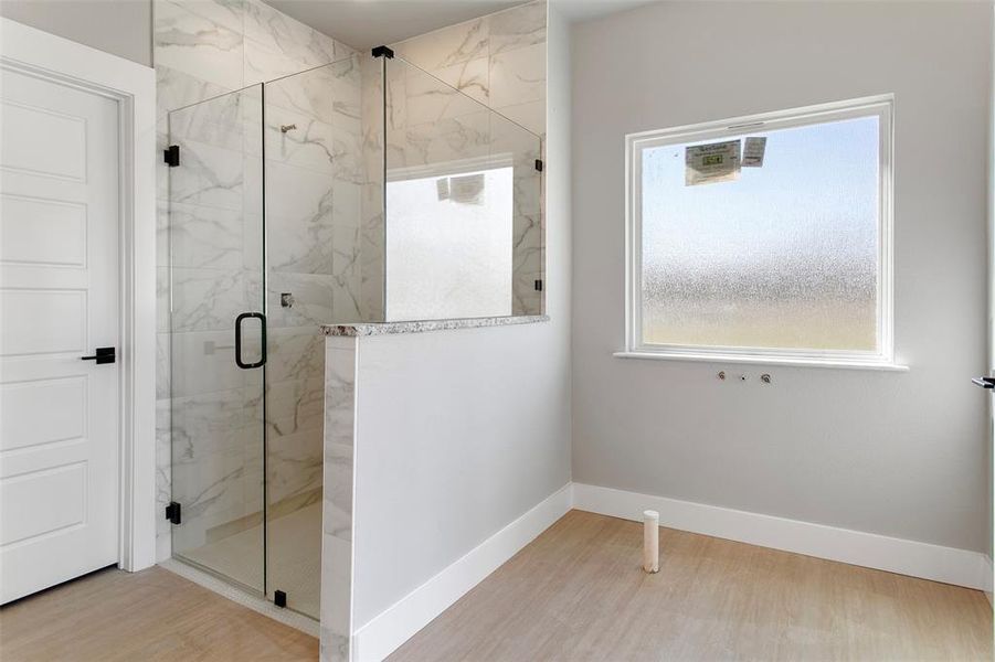 Bathroom featuring wood-type flooring and a shower with door