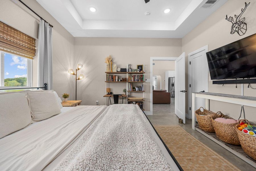 Bedroom with concrete floors, recessed lighting, stainless steel fridge with ice dispenser, and a raised ceiling