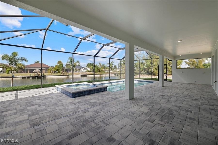View of pool featuring a lanai, a sunroom, a pool with connected hot tub, a patio area, and a water view