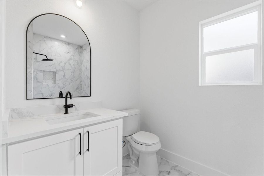 Upstairs bathroom featuring a charming shower/tub combo, a spacious vanity, and a sleek modern mirror. Frosted glass window adds privacy while still allowing plenty of natural light to fill the space.
