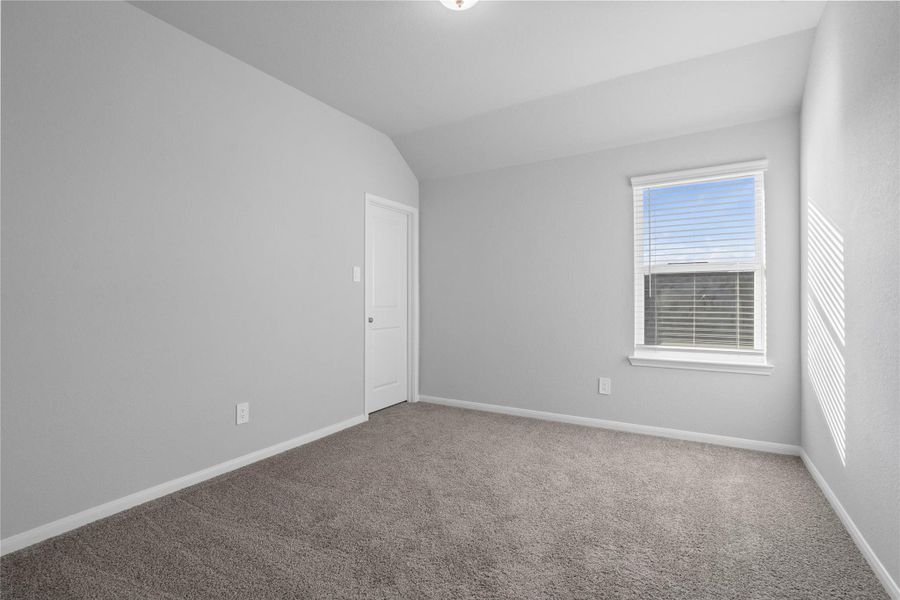This cozy secondary bedroom offers plush soft carpeting, neutral walls ready for personalization, a sun-filled window with fitted blinds, sloped ceilings, and a spacious closet for all your storage needs.