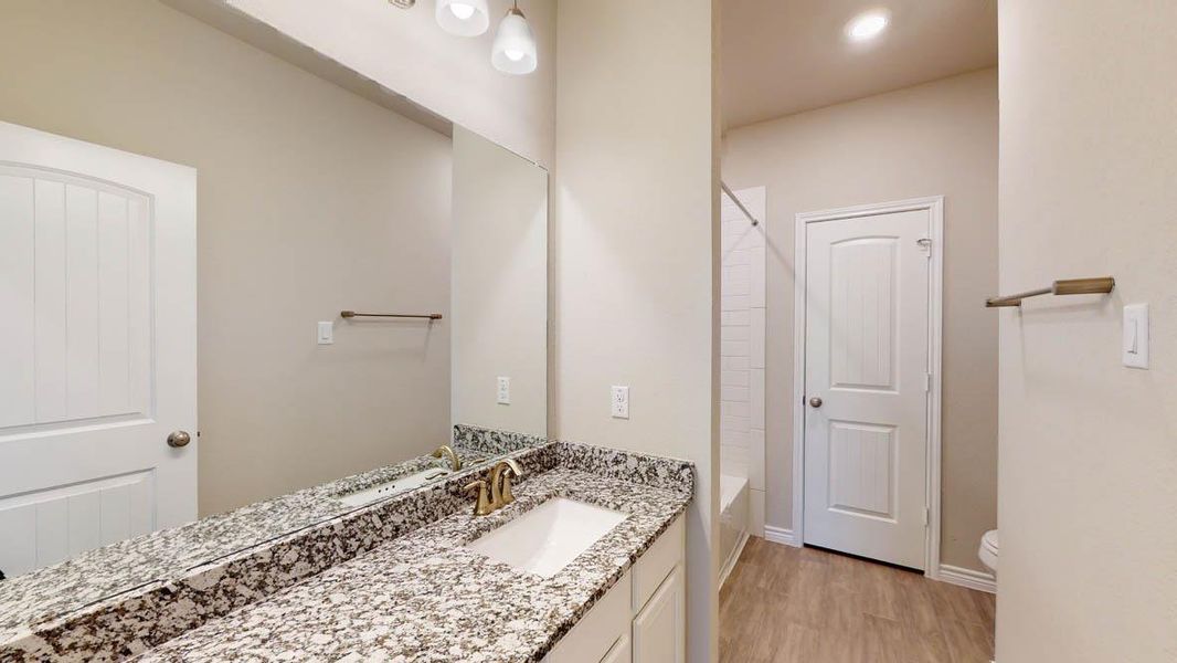 Full bathroom featuring vanity, light wood-style floors,  shower combination, and recessed lighting