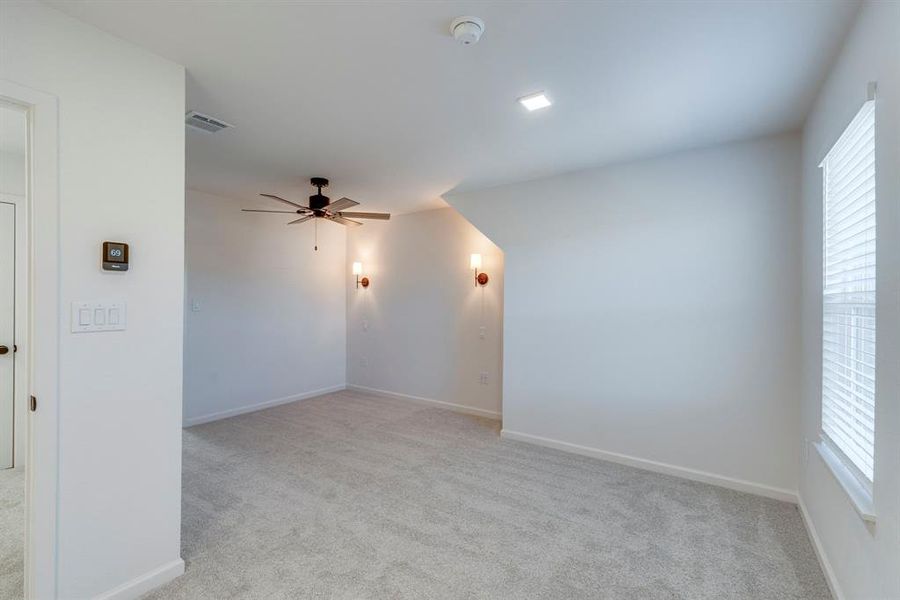 Spare room featuring light colored carpet and ceiling fan