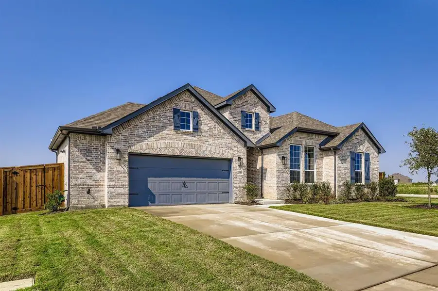 French country style house featuring brick siding, driveway, and roof with shingles