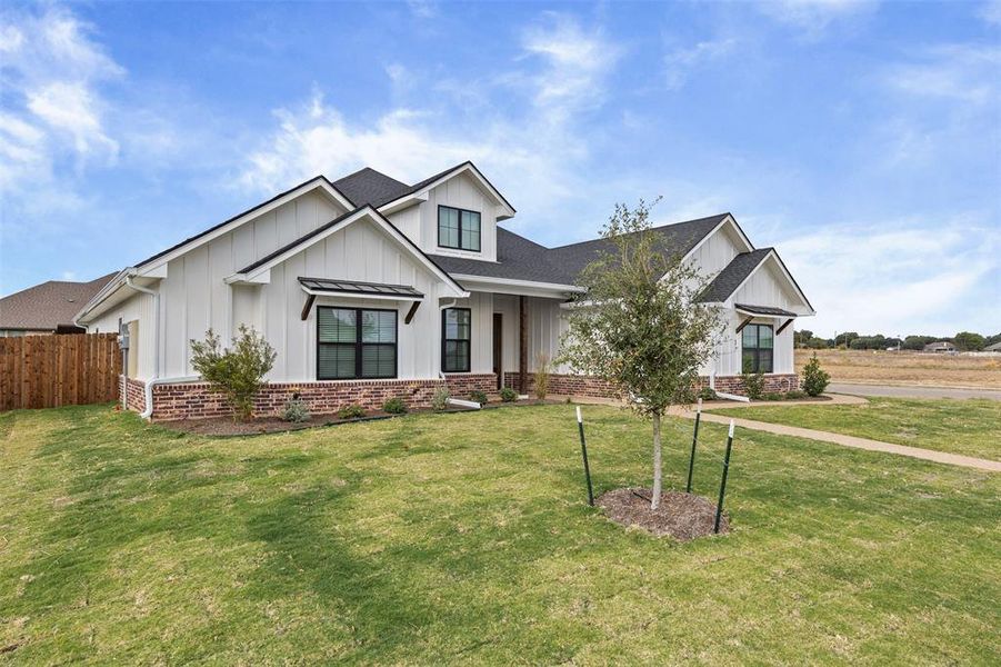Modern inspired farmhouse with board and batten siding, a porch, roof with shingles, and brick siding Modern inspired farmhouse with board and batten siding, a porch, roof with shingles, and brick siding