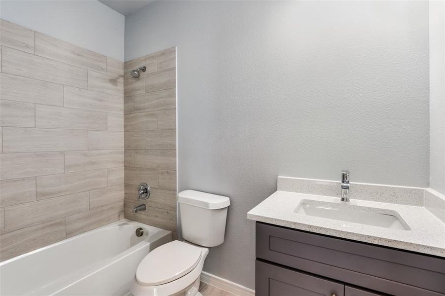 Full bathroom with vanity, tiled shower / bath combo, and toilet