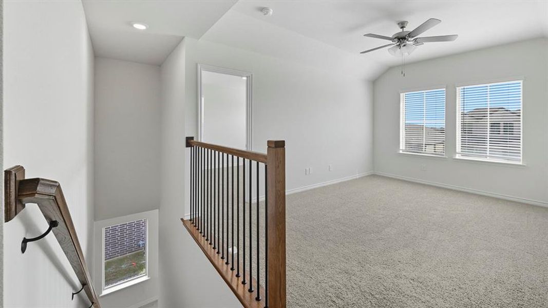 Corridor featuring carpet floors, vaulted ceiling, and an upstairs landing